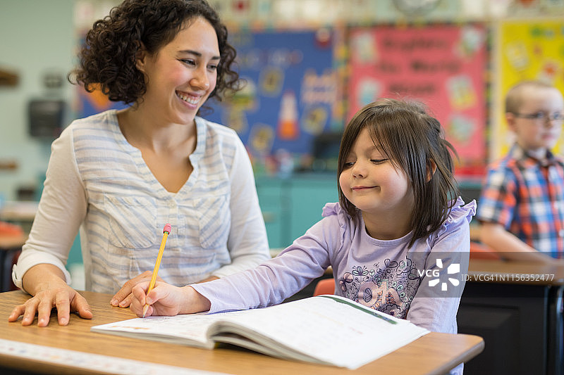 一年级女生在教室里和老师交谈图片素材