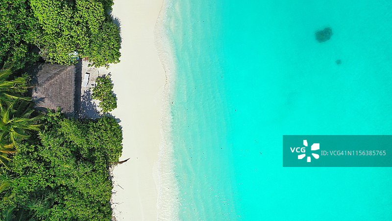 白色沙滩上热带棕榈树环绕的海滩小屋俯视图图片素材