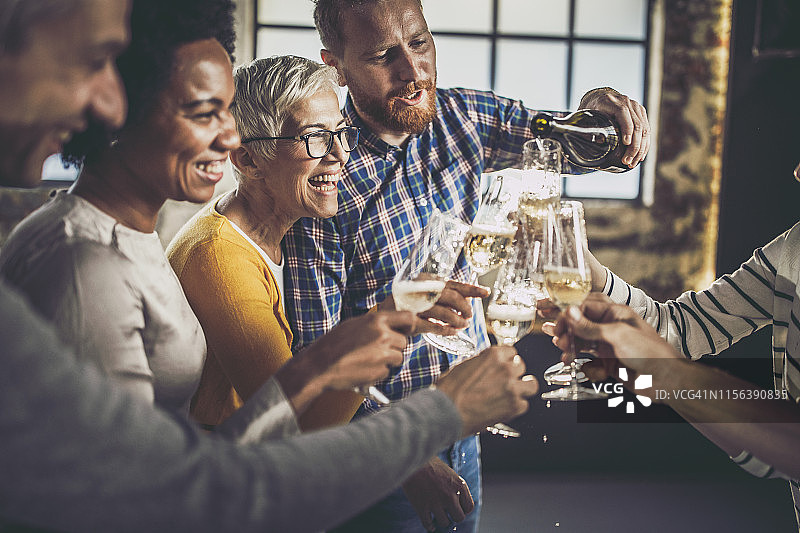 办公室派对上倒香槟的快乐商业伙伴图片素材