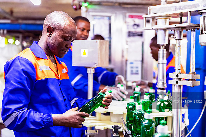 生产线工人随机检查肥皂瓶的质量问题图片素材