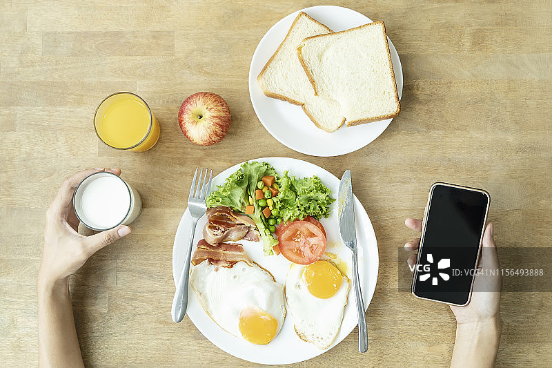 餐桌上的早餐：煎蛋、沙拉、牛奶、苹果和手机图片素材