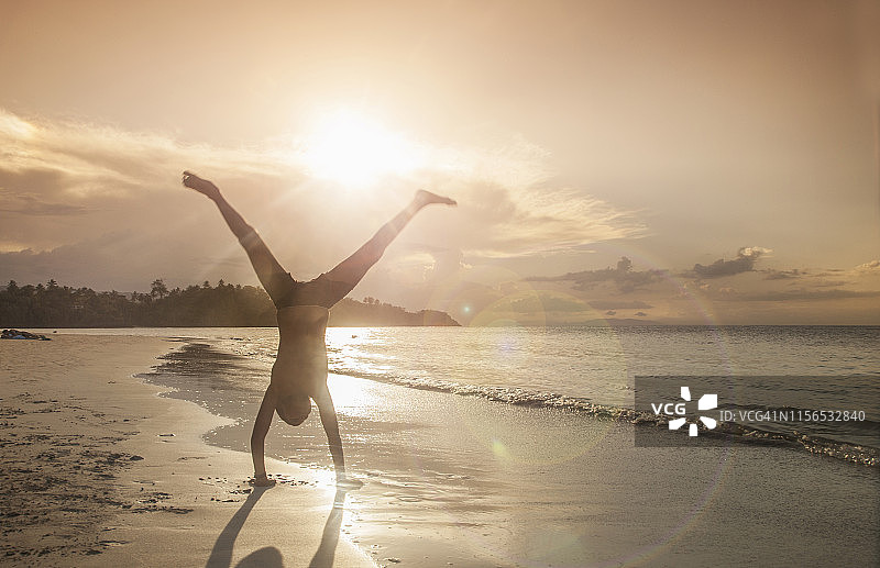 在海滩上翻跟头的男孩图片素材