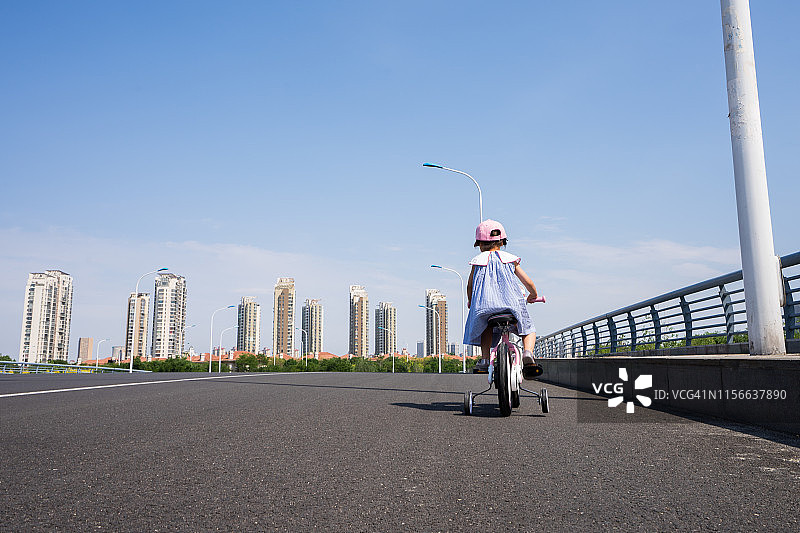 年轻女孩在路上骑自行车图片素材