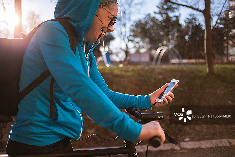 骑自行车使用智能手机的年长女运动员图片素材