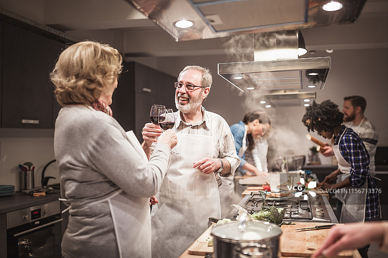 烹饪班学员与厨师一同举杯红酒，庆祝课程圆满结束图片素材