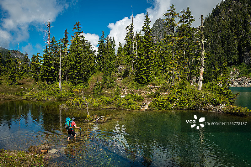 徒步者穿过湖泊走向森林图片素材