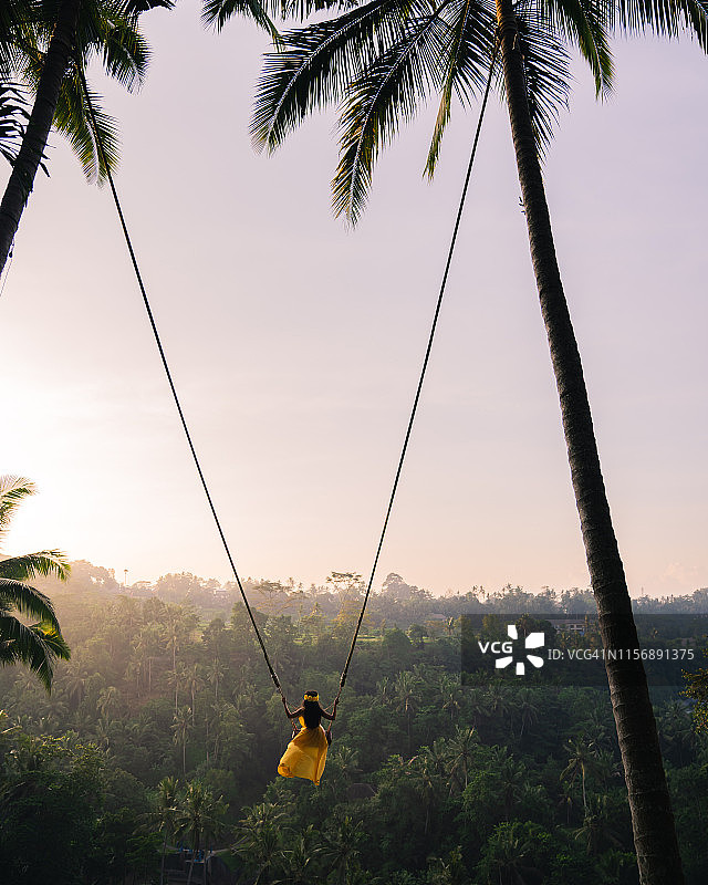 在巴厘岛丛林上荡秋千的年轻女子图片素材