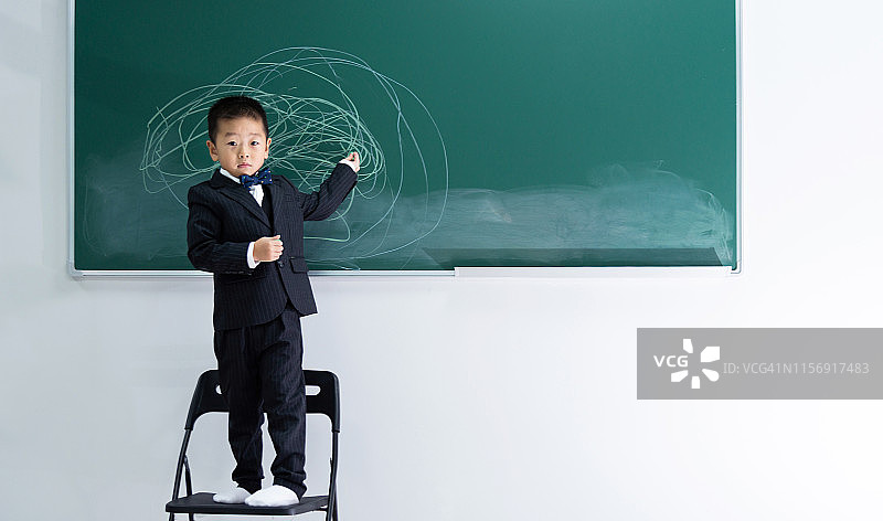 站在黑板前的小男孩：既是学生也是“教授”图片素材