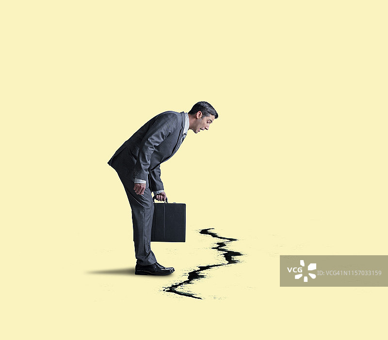 商人看着地面上的巨大裂缝图片素材