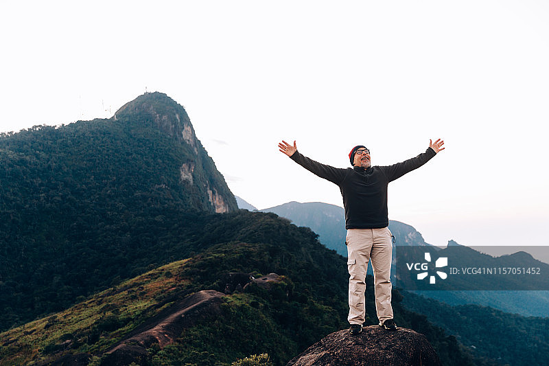 在山边户外欢呼雀跃，举起双臂的年长男人图片素材