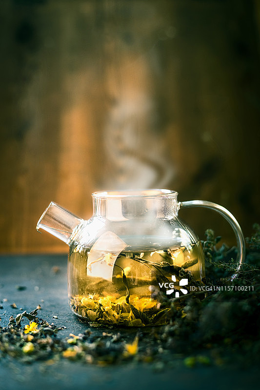 深色背景下的草药茶蒸汽茶壶图片素材
