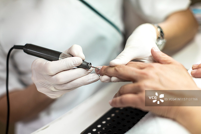 使用美甲旋转锉去除多余角质，修整指甲图片素材