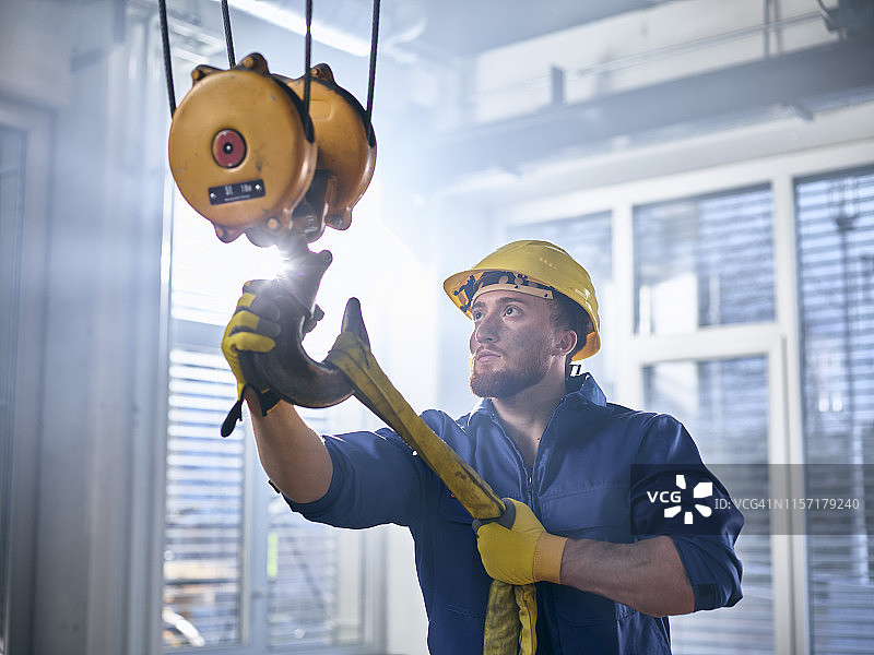 工业工人在室内起重机上固定吊索图片素材