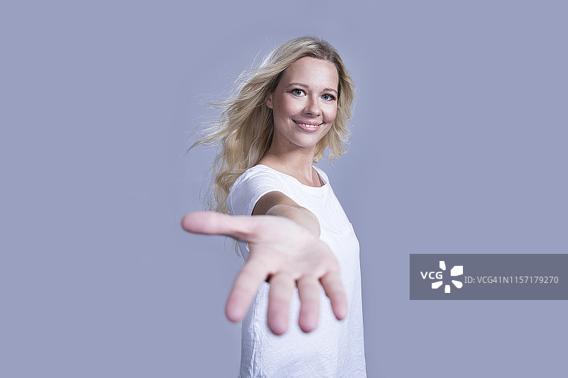 笑容满面的金发女人伸出援助之手的人像照片图片素材