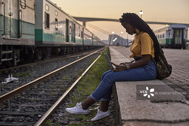 在火车站站台上使用笔记本电脑的年轻女人图片素材