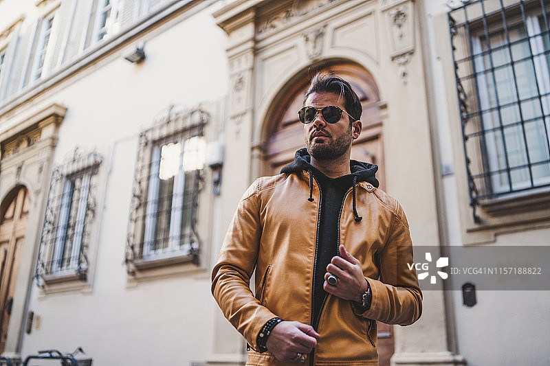意大利佛罗伦萨：戴太阳镜和浅棕色皮夹克的胡须男士肖像图片素材