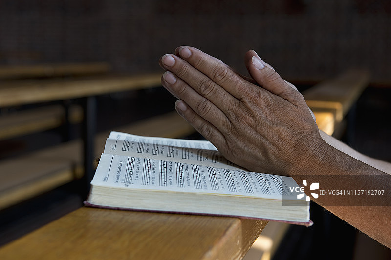 在教堂长椅上手捧赞美诗祈祷的手图片素材