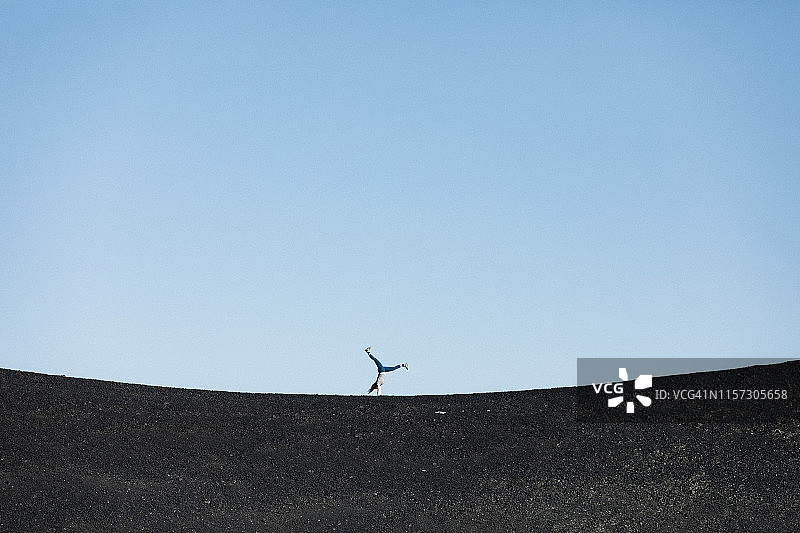 女人在月球陨石坑的黑沙上做车轮式图片素材