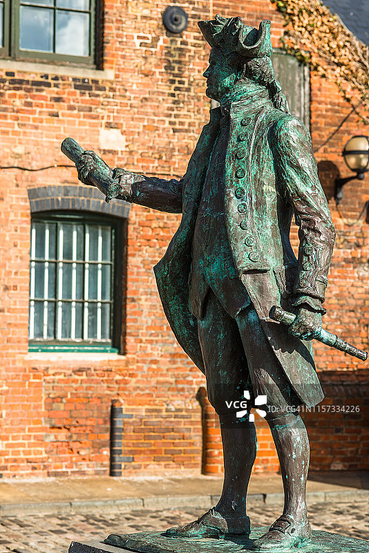 以旧仓库为背景的乔治·温哥华船长雕像，英国诺福克金斯林图片素材