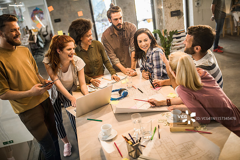 在办公室会议上讨论蓝图的年轻快乐的建筑师图片素材