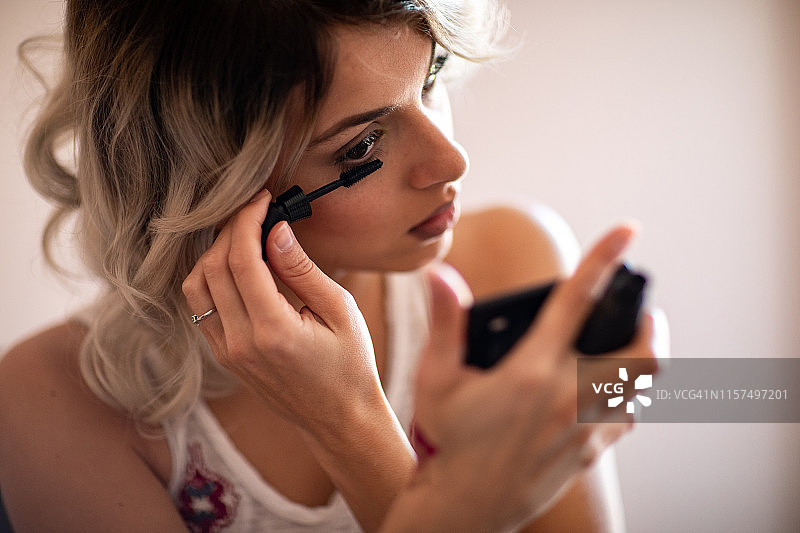 美丽的年轻女人刷睫毛膏图片素材