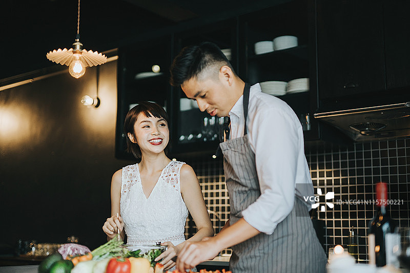 充满爱意的年轻亚洲夫妇在厨房一起准备沙拉图片素材