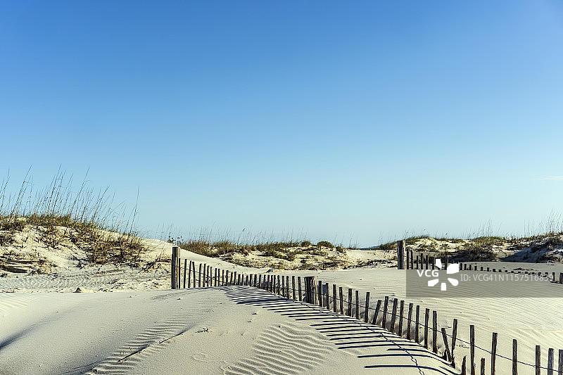 蓝天下流沙丘与防沙栅栏的阴影图片素材