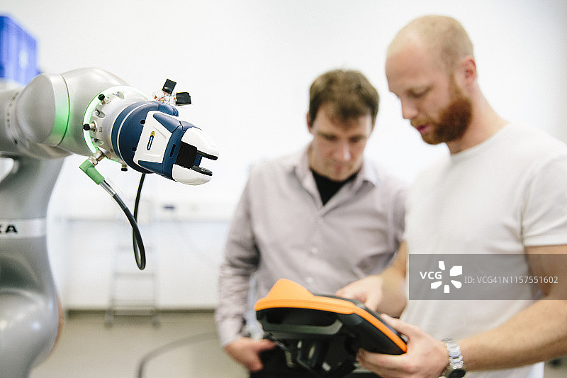 工业4.0：两位工程师在机械臂上工作图片素材