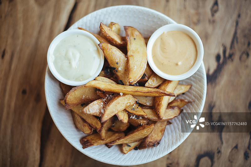 盛在白色碗中，配有黑海盐和蒜泥蛋黄酱的美味炸土豆角图片素材
