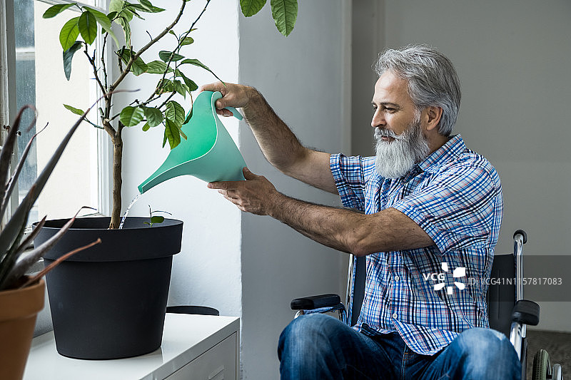 坐在轮椅上，拿着浇水壶的老年男人图片素材