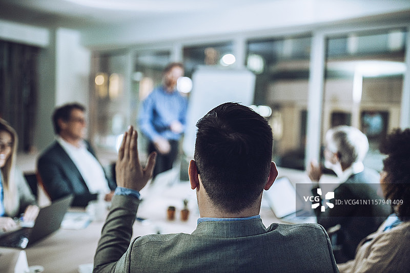 在办公室会议上提问的商人背影图片素材