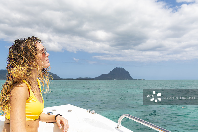 身穿比基尼的年轻女人在船上享受阳光图片素材