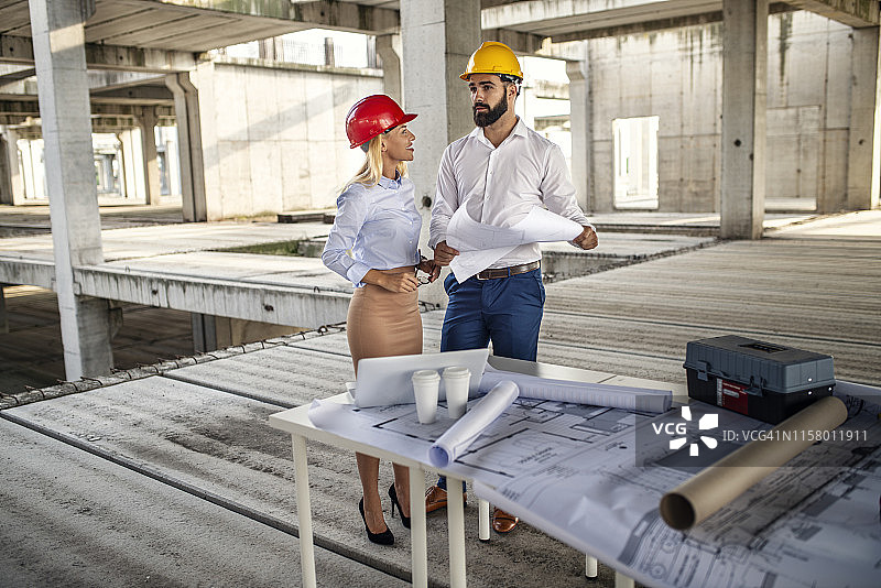 年轻男女建筑师在建筑工地查看楼层平面图图片素材