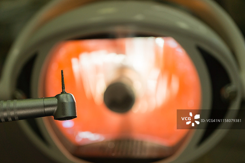 牙科诊所：牙科手机和牙钻，医疗灯背景，牙科治疗概念图片素材