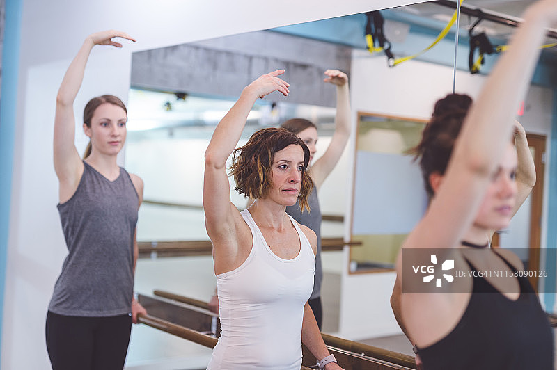 在现代健身俱乐部一起做杠铃操的多元种族女性图片素材