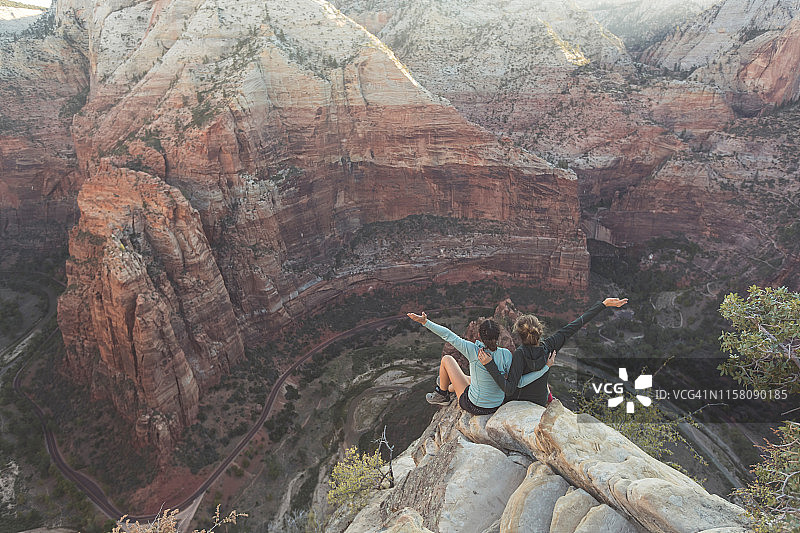 两位女徒步者坐在悬崖边图片素材