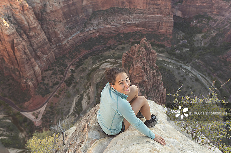 年轻女子坐在悬崖边俯瞰高速公路图片素材