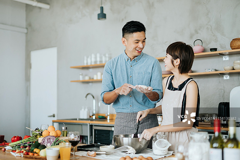 充满爱意的年轻亚洲夫妇在厨房里一起准备饼干图片素材