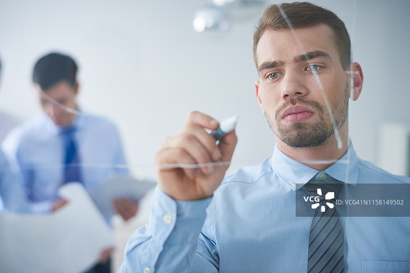 经理在会议期间在玻璃板上绘图图片素材