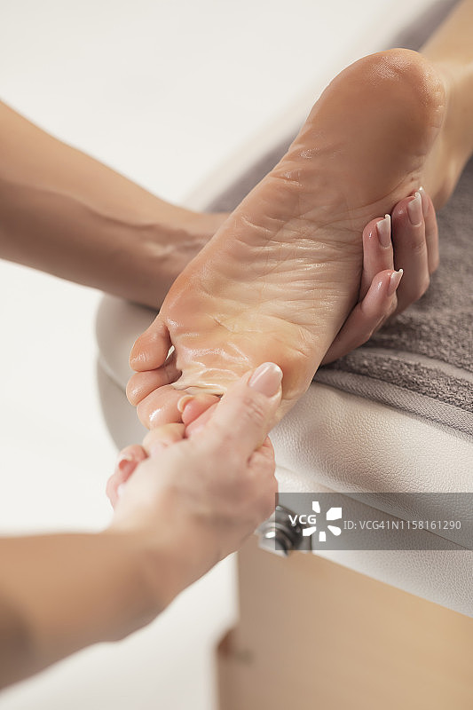 按摩理疗师进行足部按摩：健康水疗护理中的放松按摩图片素材