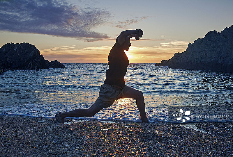 在日落时分的海滩上练习双拳功夫的男人图片素材