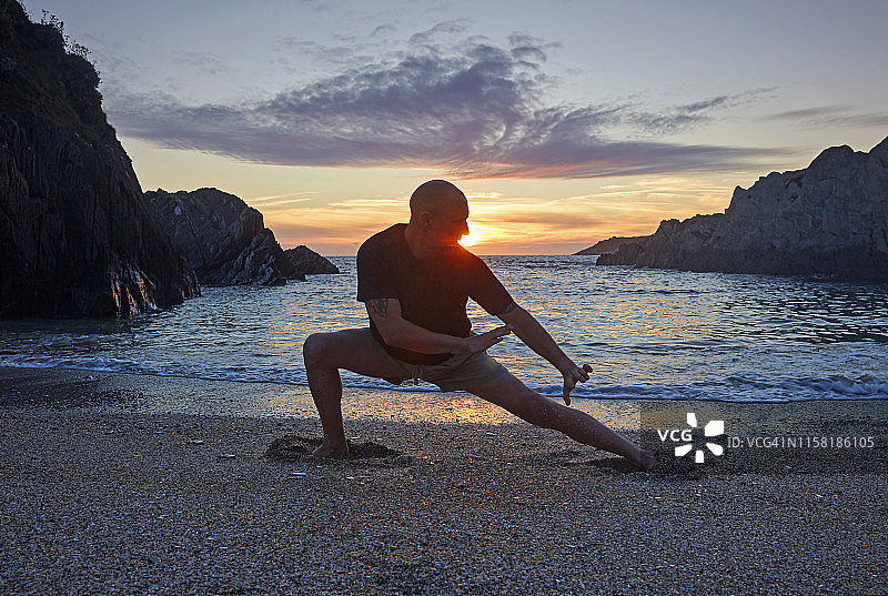 男人在日落时在海滩上练习少林功夫图片素材