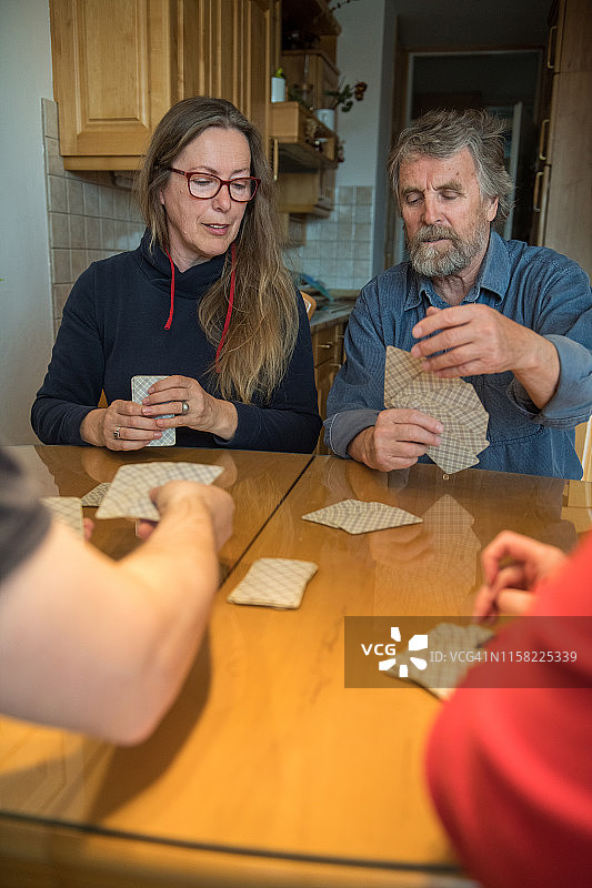 年长夫妇和千禧一代夫妇在家玩牌图片素材