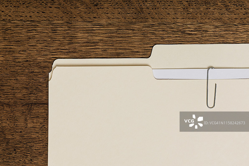 从上方看到的马尼拉文件夹和木质表面的回形针图片素材