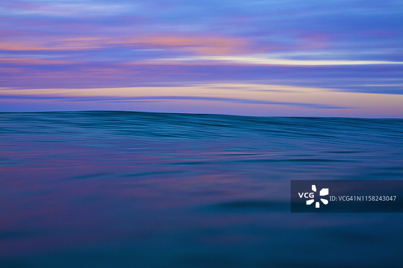 墨西哥纳亚里特州萨尤利塔日出时分宁静的粉蓝色海洋和天空图片素材