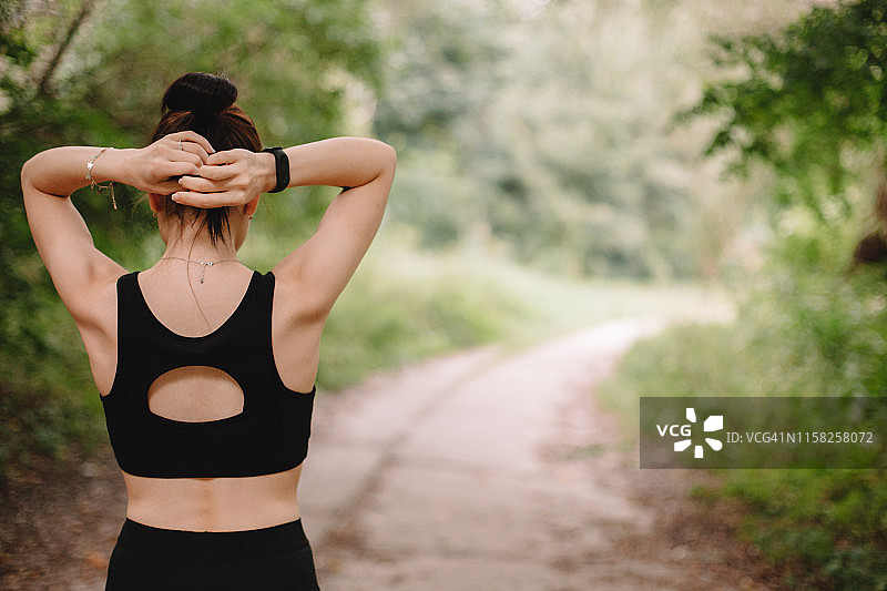 在公园里扎头发的女慢跑者的背影图片素材