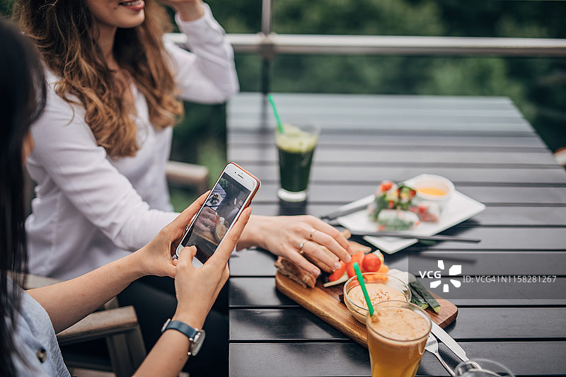 女人用智能手机拍摄食物照片图片素材