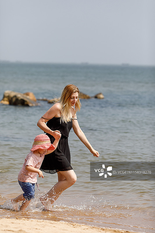 小女孩和她的母亲在海边奔跑图片素材