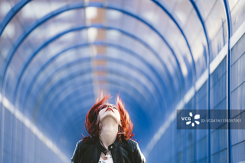 红色头发的女人向上看，头发飘逸图片素材