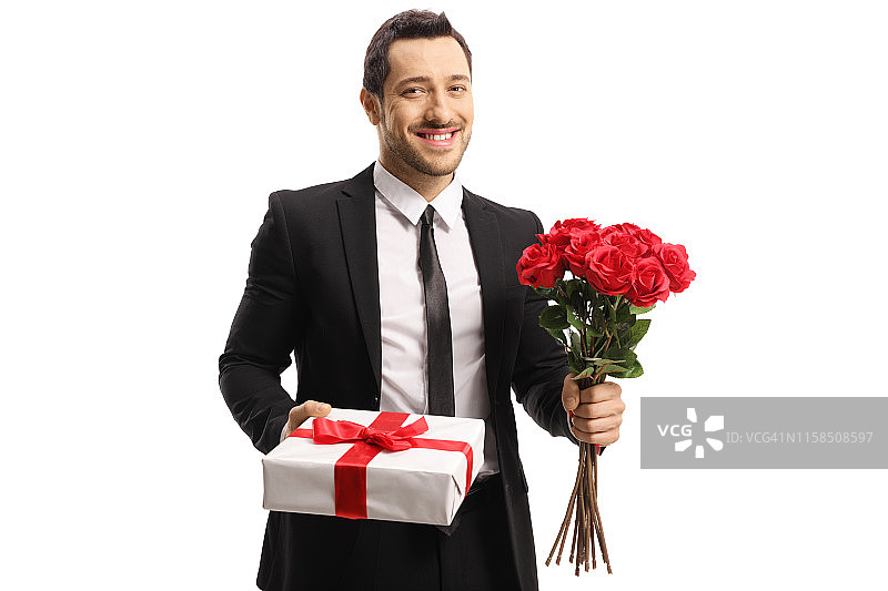 手持一束红玫瑰和礼物的英俊青年图片素材